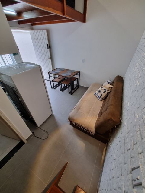 Sala com sofá-cama e parede de tijolinho branco